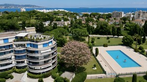 A multi-story hotel with a pool, surrounded by greenery and a view of the sea. - Apartment for 4, pool, AC, WiFi, parking, 300m from the beach (Mandelieu-la-Napoule)