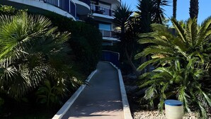 A multi-story building with balconies, surrounded by palm trees and a pathway. - Apartment for 4, pool, AC, WiFi, parking, 300m from the beach (Mandelieu-la-Napoule)