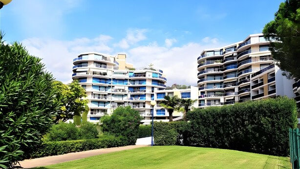 A modern multi-story hotel with balconies, a well-maintained lawn, and a clear sky. - Apartment for 4, pool, AC, WiFi, parking, 300m from the beach (Mandelieu-la-Napoule)