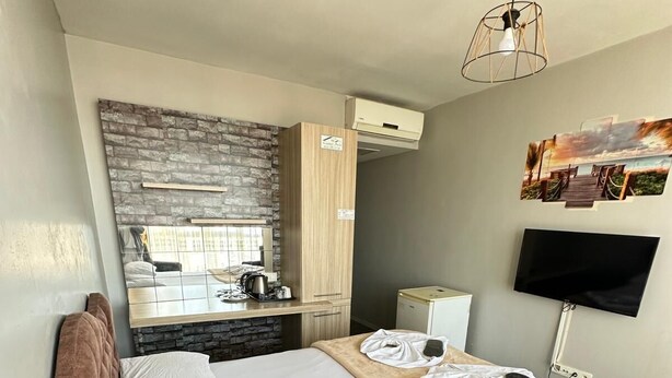 Una habitación de hotel con una cama grande, kitchenette, una televisión de pantalla plana y una pared de piedra.