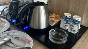 Una encimera de cocina con una tetera, vasos y una bandeja con un vaso y utensilios.