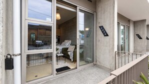 Un apartamento moderno con balcón, puertas correderas de vidrio amplias y vistas a la calle.