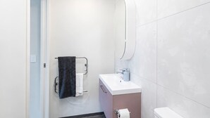 Un baño moderno con un lavamanos blanco, un espejo y un perchero para toallas.