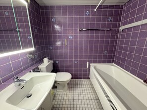 Un baño con azulejos morados, un lavamanos blanco, un inodoro y una bañera.