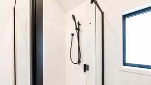 A shower area with a window, a towel rack, and a door. - 1BR with Courtyard + Parking | Near CBD (Christchurch)