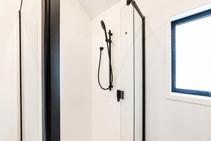 A shower area with a window, a towel rack, and a door. - 1BR with Courtyard + Parking | Near CBD (Christchurch)