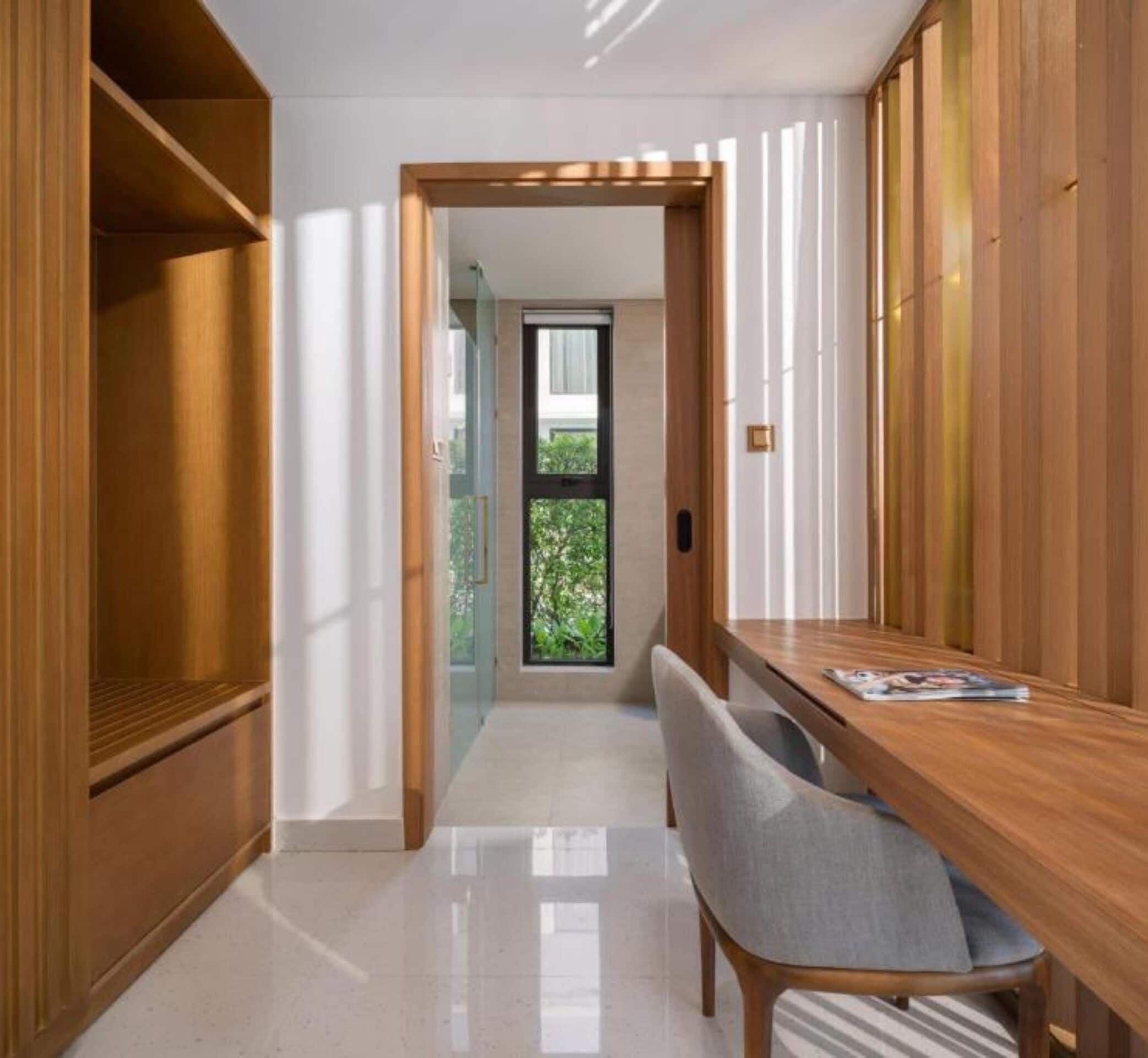 Un intérieur moderne avec un bureau en bois, une chaise et une porte vitrée donnant sur un balcon.