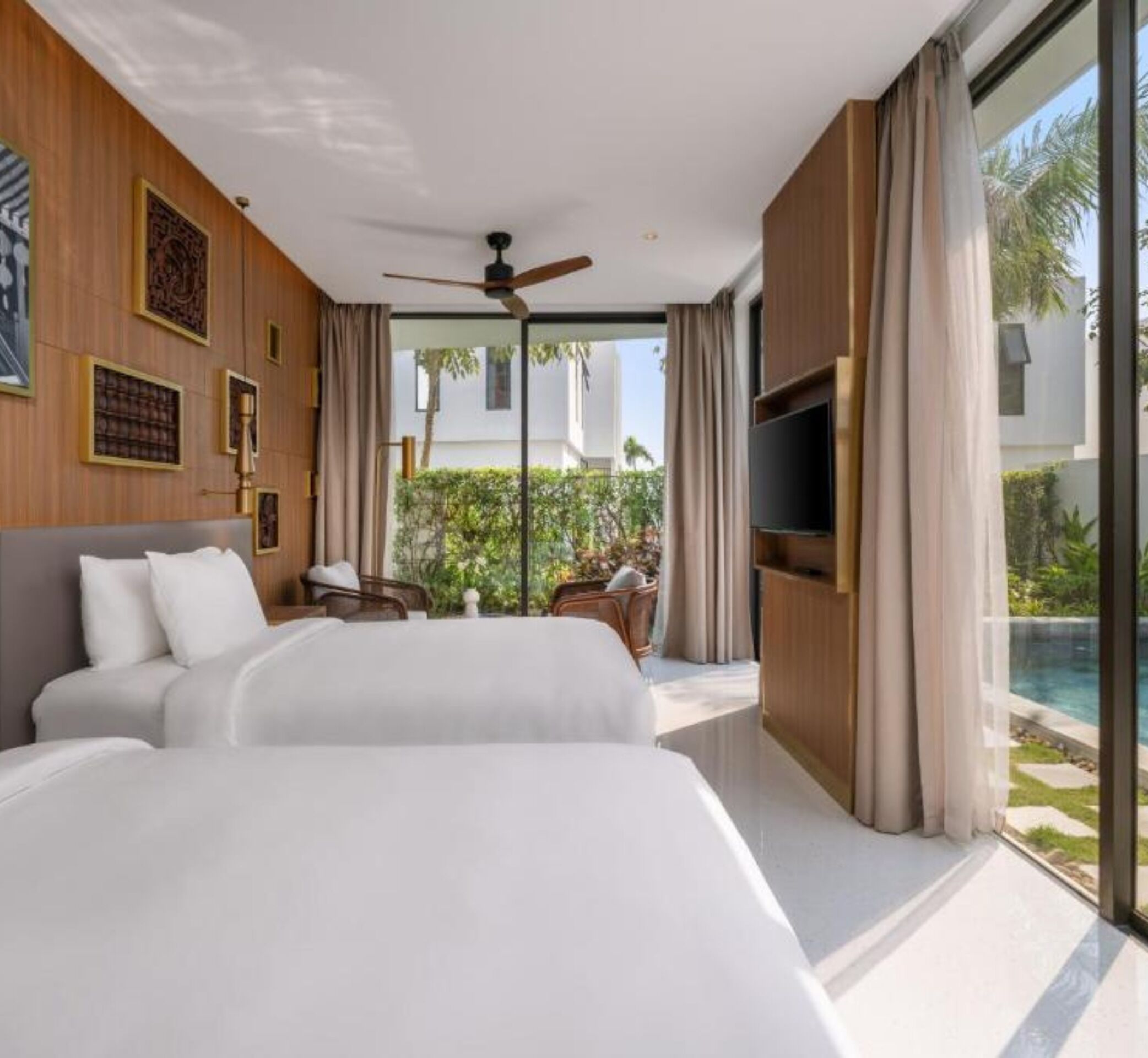 A modern hotel room with a large bed, a ceiling fan, a TV, and a view of a swimming pool.