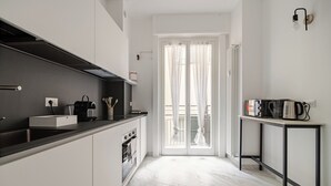 Une cuisine moderne avec des meubles blancs, un plan de travail noir et un four encastré.