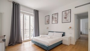 Une chambre à coucher moderne, avec un lit, des tables de chevet et une vue sur l’extérieur.