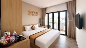 Habitación de hotel con una cama grande, un televisor de pantalla plana, un balcón con cortinas y un panel de madera en la pared izquierda.