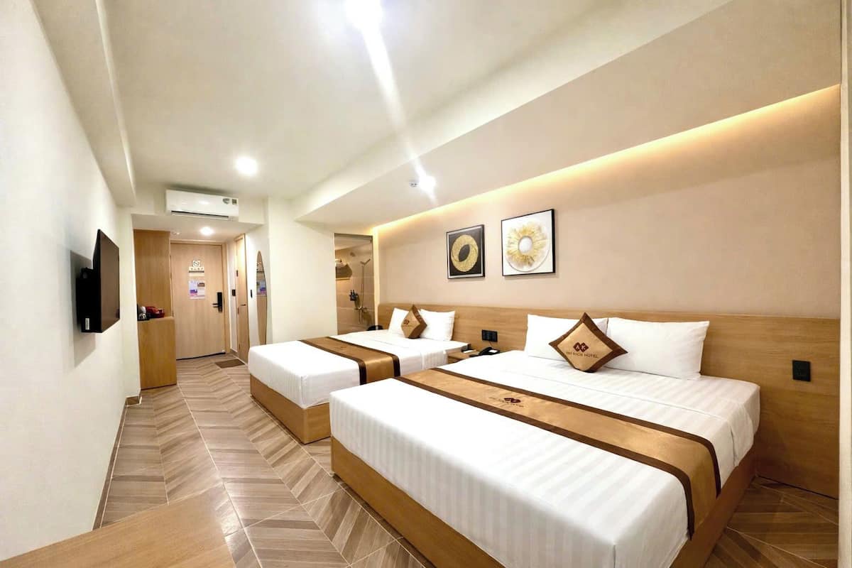 A hotel room with two beds, a TV, and a shower area.