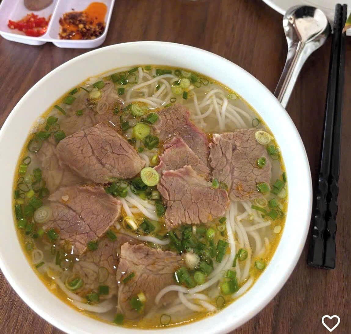 Un bol de soupe de nouilles au bœuf, garni d’émincés de bœuf, de nouilles et d’oignons verts.
