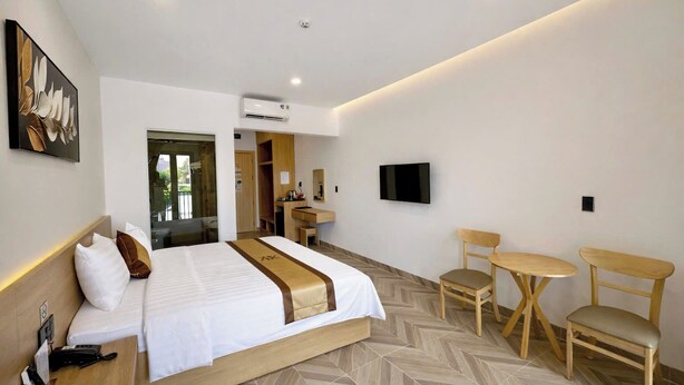 Una habitación de hotel con cama, escritorio, silla, televisor y aire acondicionado.
