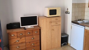 A compact kitchen with a wooden cabinet, a microwave, a small refrigerator, and a trash bin. - Large studio with view of Salses lake (Le Barcarès)