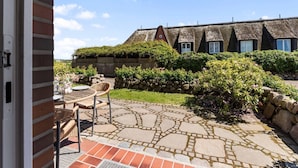 A patio with stone flooring, a wicker chair, and a table.
