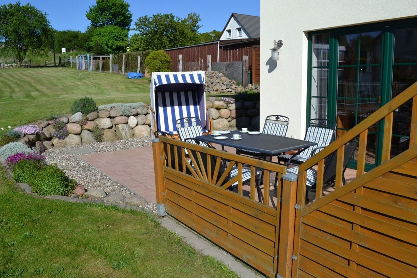 A patio with a table and chairs, a wooden fence, and a stone wall.