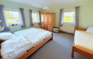 A bedroom with two beds, a wooden wardrobe, a radiator, and a window with curtains. - Vacation apartment Guder - top for families without a car - Large vacation apartment, with (Binz)