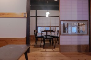 Una habitación con piso de madera, una mesa, sillas y una lámpara colgante.