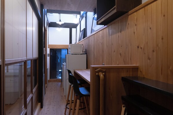 Una cocina estrecha con paredes de madera, una mesa de madera y dos sillas negras.