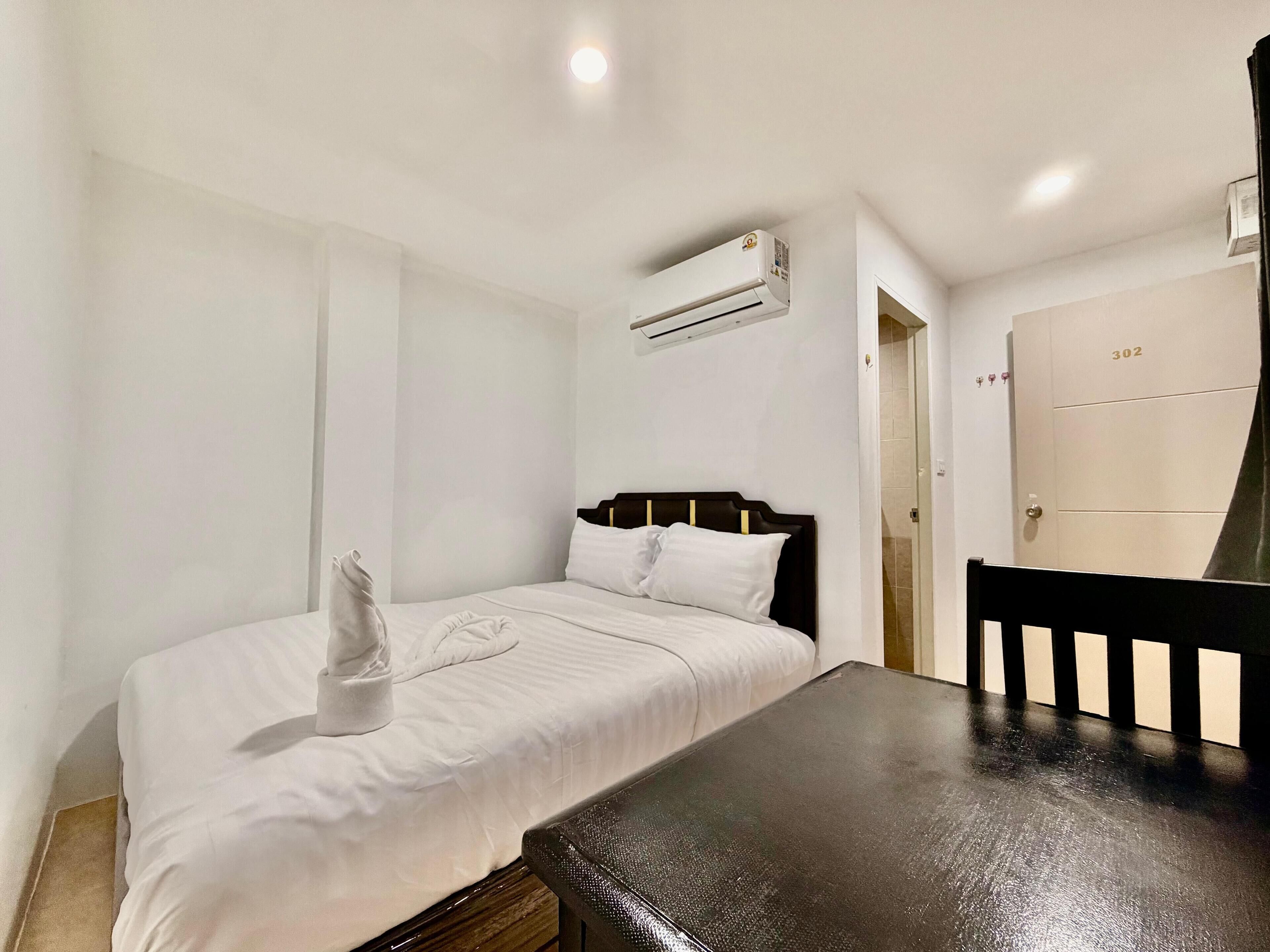 Habitación de hotel con cama, una mesa, un equipo de aire acondicionado y una puerta con el número 302.