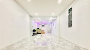 A corridor with a marble floor, white walls, and a reception desk with a computer and a plant. - Jasmine Residence (Patong)