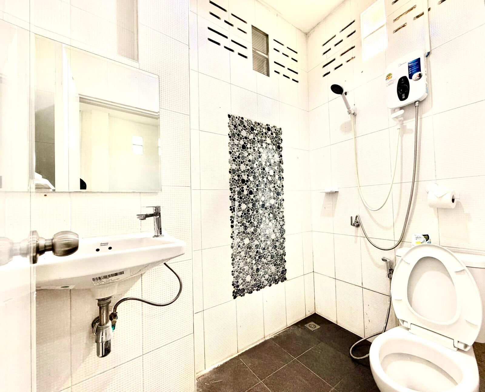 A small, modern bathroom with a white sink, a toilet, and a shower.