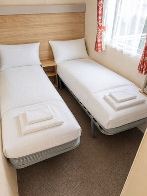Una cama doble con cabecera de madera, una mesita de noche y una ventana con cortinas.