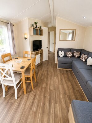 A modern living room with a grey sofa, wooden dining table, and chairs.
