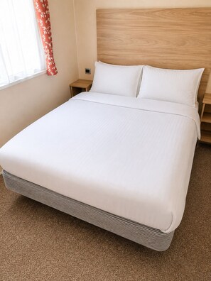 A hotel room with a bed, wooden headboard, and a nightstand.