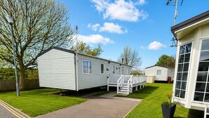 Ein Caravanpark mit befestigtem Weg, Rasenflächen und einem weißen Gebäude mit großen Fenstern.