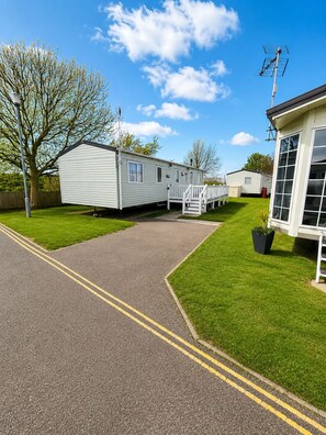 A caravan park with a paved pathway, grassy areas, and a white building with large windows.