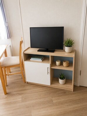 A room with a wooden desk, a television, a chair, and a cabinet.