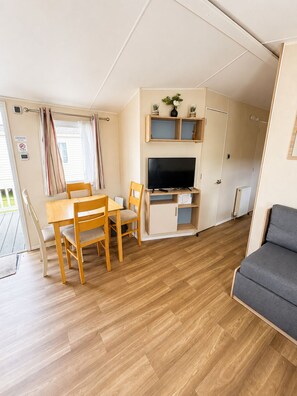 A compact living space with a dining table, chairs, a TV, and a sofa.