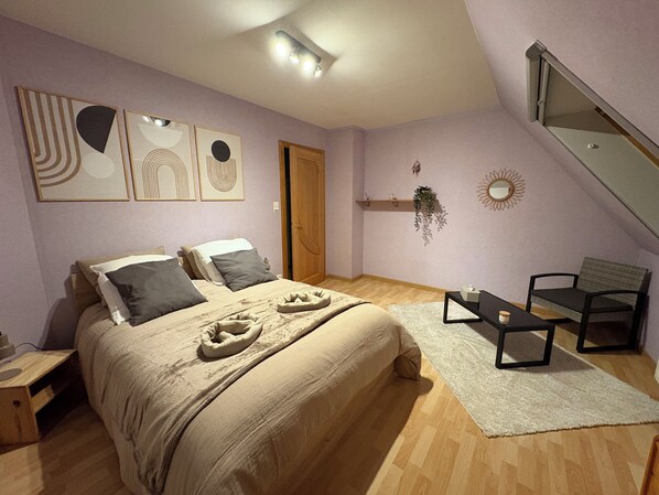 A bedroom with a bed, a chair, a desk, and a window.