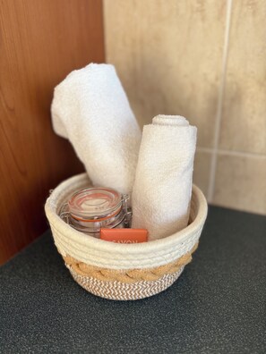A woven basket containing a jar and a bar of soap on a countertop.