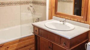 A bathroom with a wooden vanity, a bathtub, and a large mirror. - Studio chaleureux avec vue montagne au cœur de Font-Romeu (Font-Romeu-Odeillo-Via)