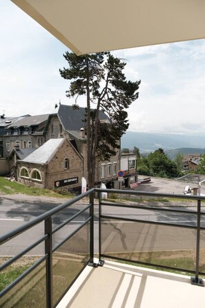 A balcony with a view of a town, including a building with a sign that reads "Ski Republic". - Studio cabine avec balcon ensoleillé pour 6 personnes en hyper-centre (Font-Romeu-Odeillo-Via)
