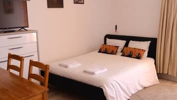 Un dormitorio con cama, mesitas de noche, un escritorio y sillas.