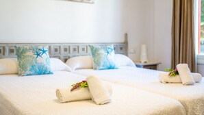 Een hotelkamer met twee bedden, elk voorzien van een witte spreidek en decoratieve kussens.