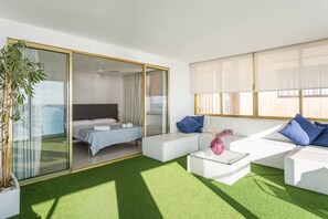 Moderni hotellihuone, jossa on sänky, sohva, sohvapöytä ja suuri ikkuna.