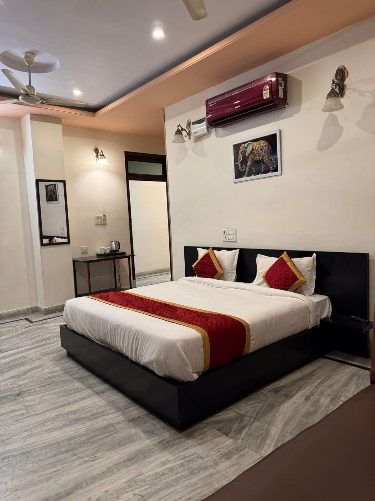 Quarto moderno com uma cama grande, um ventilador de teto, aparelho de ar condicionado e uma obra de arte na parede.