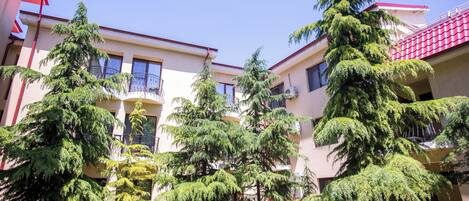 A courtyard with multiple trees and a building with balconies.