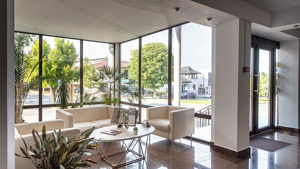 A spacious lobby with large windows, a coffee table, seating area, and potted plants.
