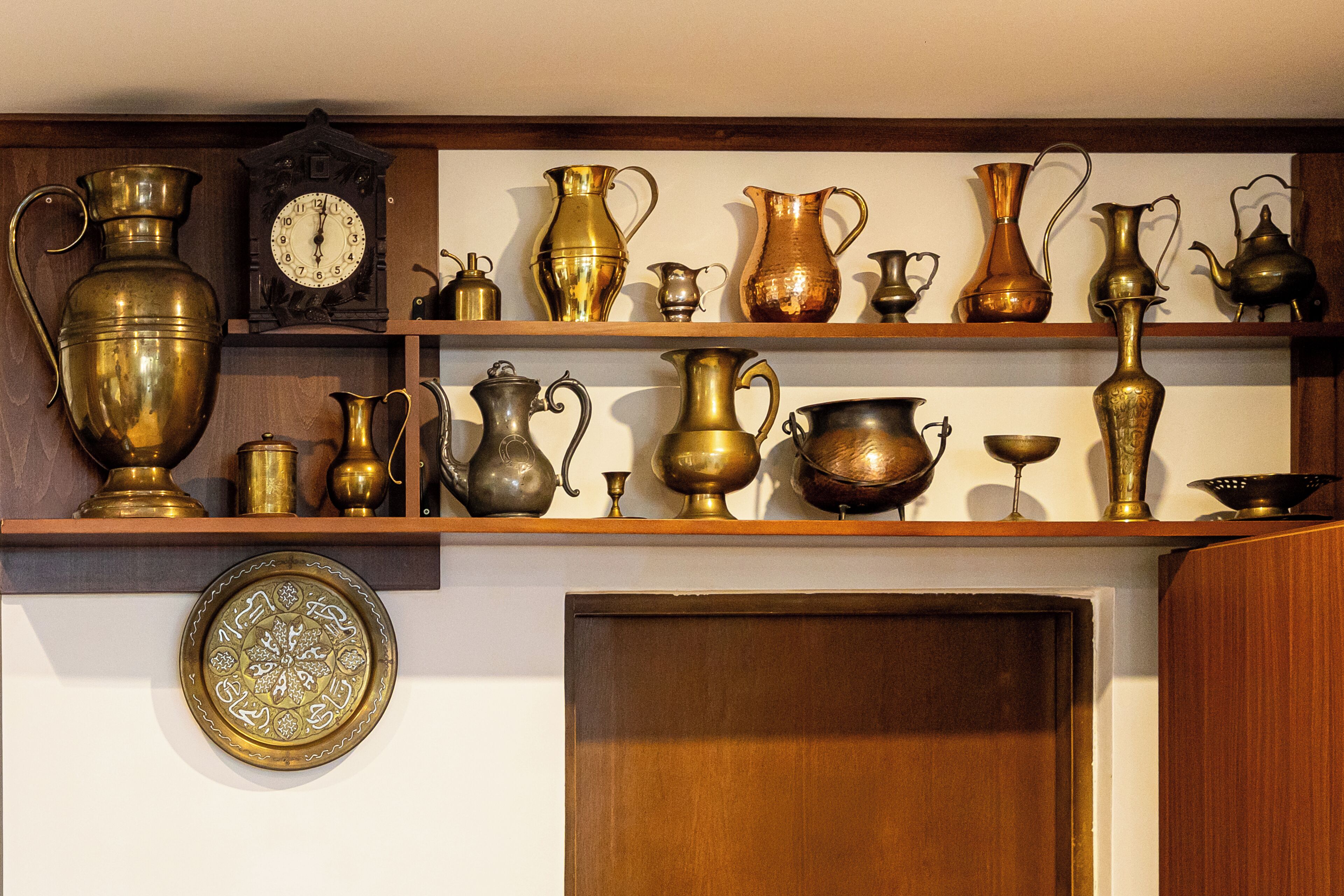 Una colección de ollas y jarrones de bronce y cobre sobre estantes.