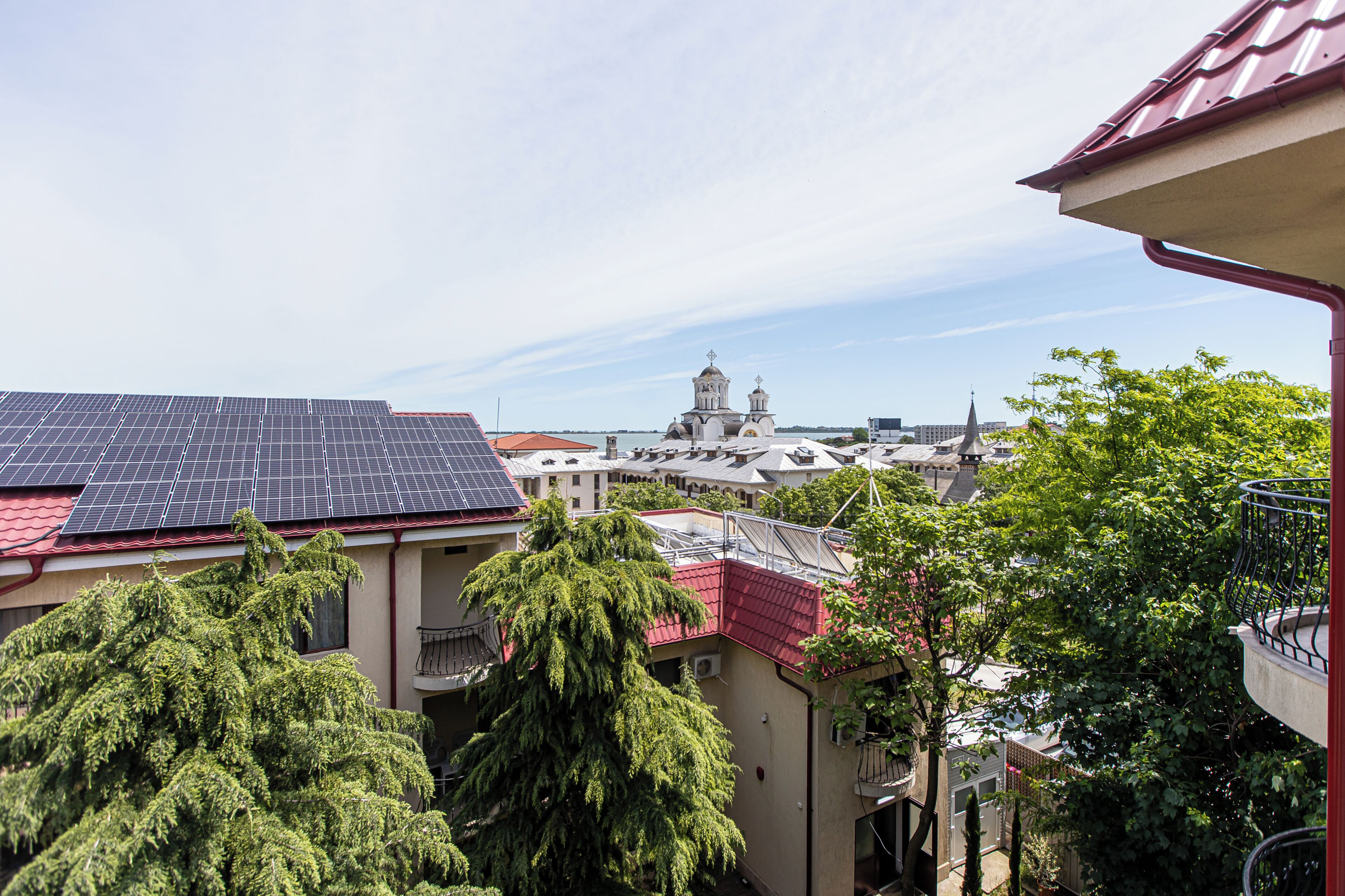 A residential area with solar panels, a church, and lush greenery.