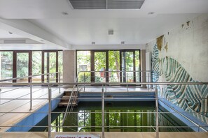 Ein Schwimmbecken mit Fliesen umrandet, eine Treppe und große Fenster.