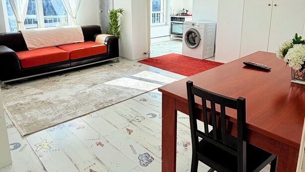 En moderne lejlighed med spiseplads, sofa, vaskemaskine og udsigt over byen.