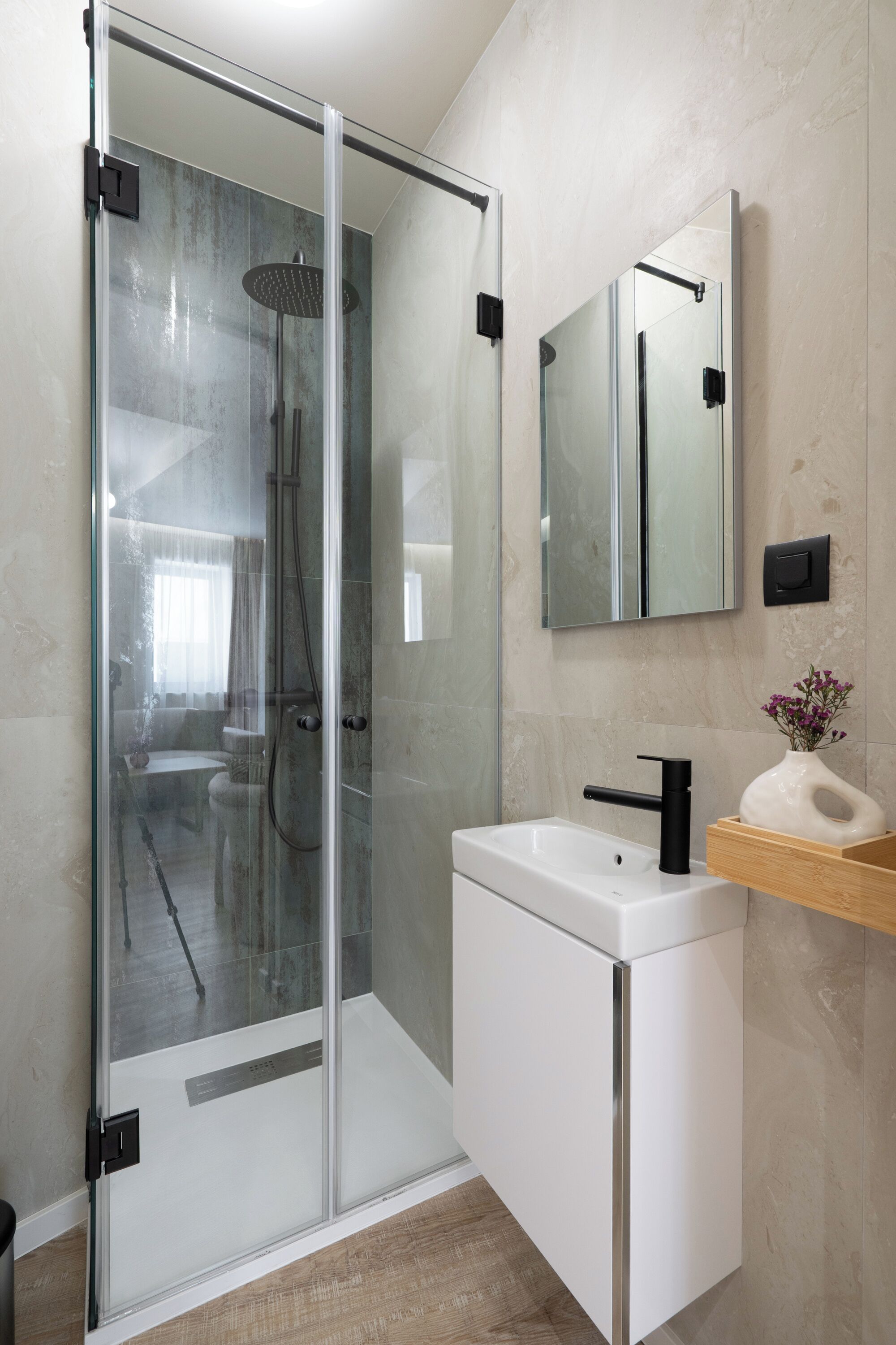 A modern bathroom with a glass-enclosed shower, a white sink, and a wooden vanity.