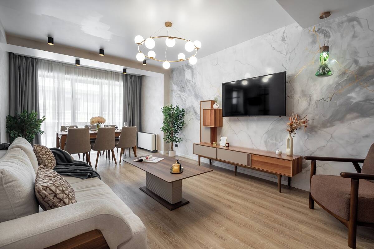 Una sala moderna con un sofá, una mesa de centro, televisor y un comedor con sillas y una mesa.